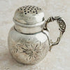 Silver shaker with decorative handle on a light background