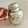 Silver shaker with decorative handle held by a hand