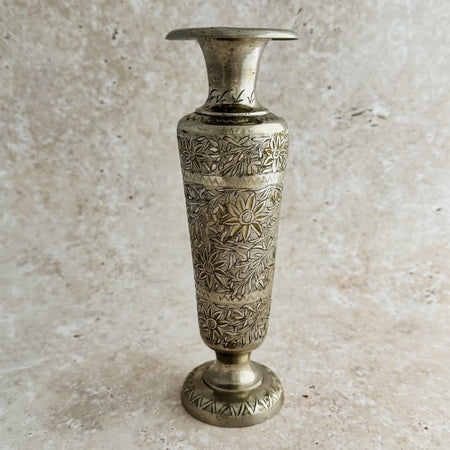 Decorative engraved bud vase with intricate patterns on a beige background