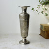 Vintage silver-colored brass bud vase with engraved floral decoration, narrow flared neck, and round footed base.