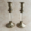 Pair of vintage silverplate and Lucite candlesticks with clear cylindrical stems, turned silverplate collars, and wide domed bases, shown against a stone-textured background