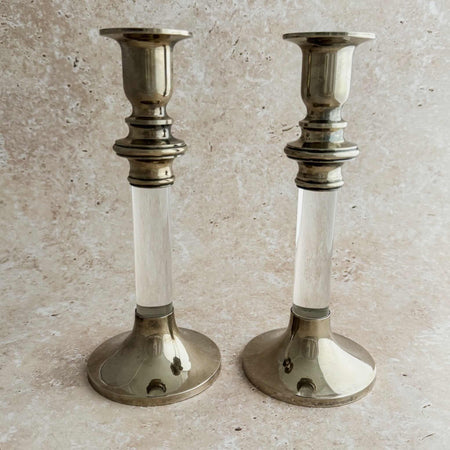 Pair of vintage silverplate and Lucite candlesticks with clear cylindrical stems, turned silverplate collars, and wide domed bases, shown against a stone-textured background