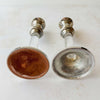 Underside view of vintage silverplate and Lucite candlestick pair showing bases — one with original brown flocked cover, one with exposed silverplate interior