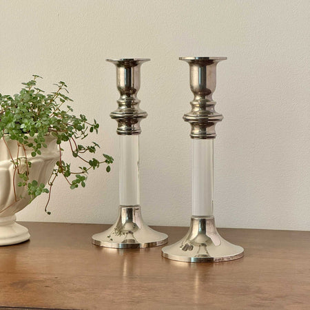 Pair of vintage silverplate and clear lucite candlestick holders, styled on a wood surface with trailing plant