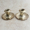 Two vintage silver Art Deco candle holders on a beige surface