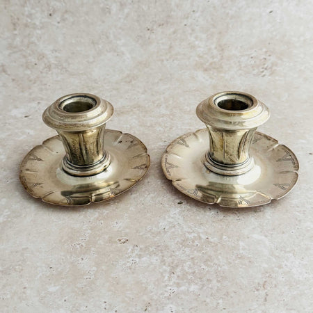 Two vintage silver Art Deco candle holders on a beige surface