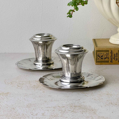 Pair of vintage silverplate candlestick holders with low scalloped bases, flared stems, and geometric Art Deco decoration.