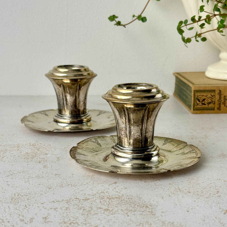 Pair of vintage silverplate candlestick holders with low scalloped bases, flared stems, and geometric Art Deco decoration.