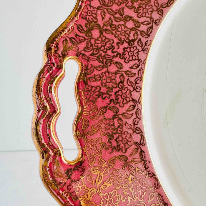 Close-up of cake plate handle cutout in pink and gold floral border