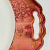 Close-up of cake plate handle cutout in pink and gold floral border