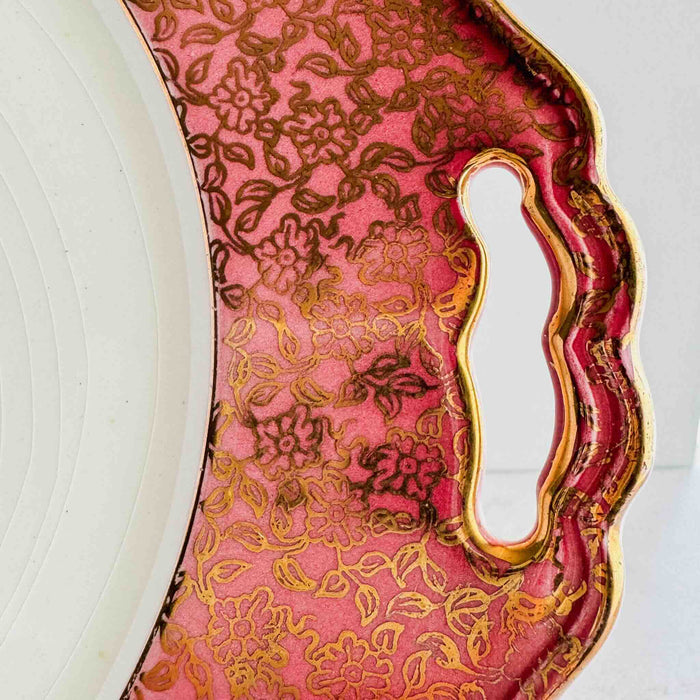 Close-up of cake plate handle cutout in pink and gold floral border