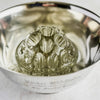 Styled view of the 19-hole glass frog placed in an engraved silver bowl