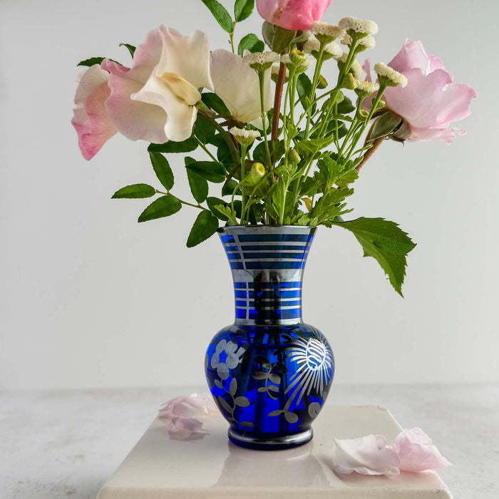 Cobalt blue and silver vase styled with flowers against a light background