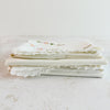 Stacked folded embroidered pillowcases - End view