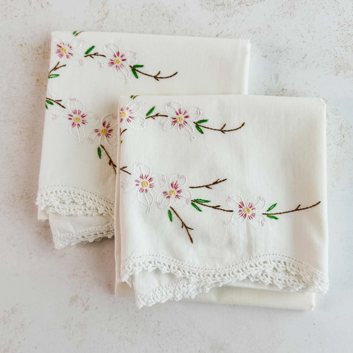 Pair of folded vintage embroidered pillowcases against a light background