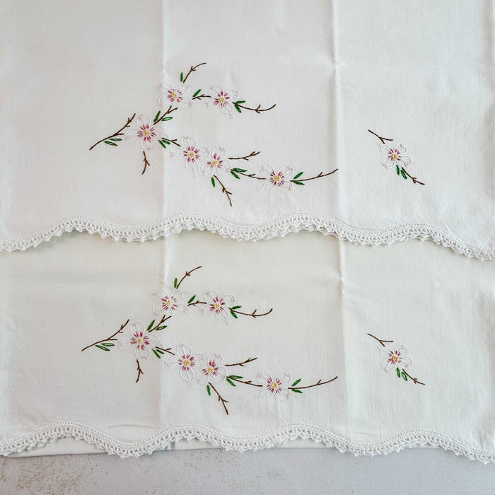 Unfolded pillowcases showing floral embroidery and crochet edges