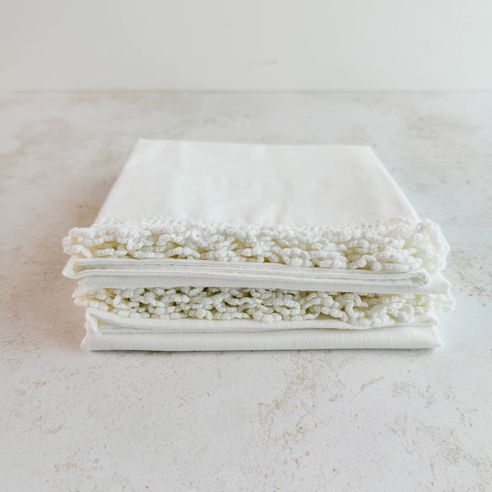 Stacked folded pillowcases showing lace edging - angled top down view