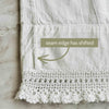 Close-up of the second white pillowcase showing the side seam shifted inward above the crochet lace edge with an arrow and condition note