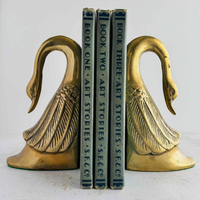Pair of Mid-Century brass swan bookends styled with books against a light background