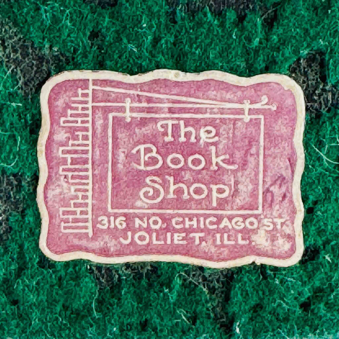 Close-up of retailer sticker reading "The Book Shop, 316 No. Chicago St., Joliet, ILL" on green felt