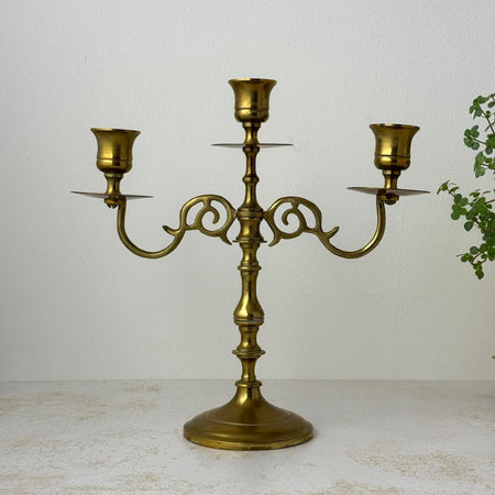 Vintage brass three-arm candelabra with scrolled arms and round pedestal base