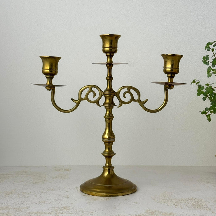 Vintage brass three-arm candelabra with scrolled arms and round pedestal base