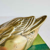 Close-up of brass duck wing showing raised feather design, patina, and vintage surface wear