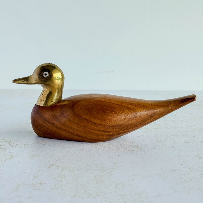 Wood and brass duck against a light background