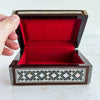 Inlaid wood box with a hand lifting the lid showing red interior