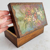 Vintage wooden keepsake box with floral design on lid held open by a hand