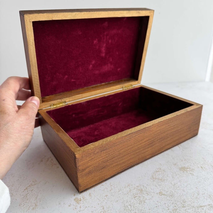 Vintage wooden box held open showing plum flocked interior