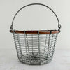 Front view of wire and twig basket with handle raised against a light background