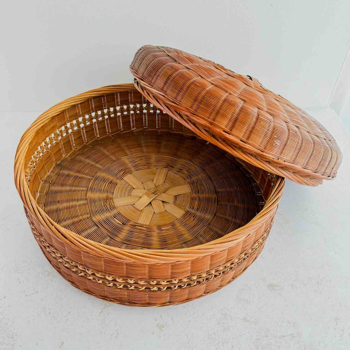 Woven basket with a lid resting against side of basket