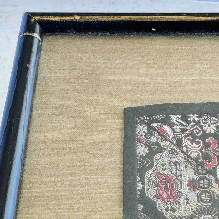 Close-up of corner of black and gold bamboo frame and gold silk texture mat