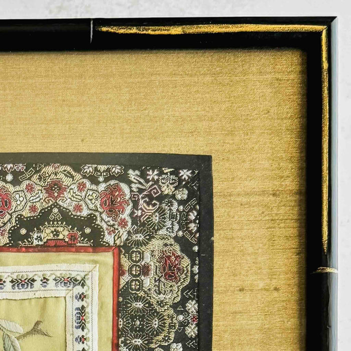 Close-up of corner of black and gold bamboo frame and gold silk texture mat