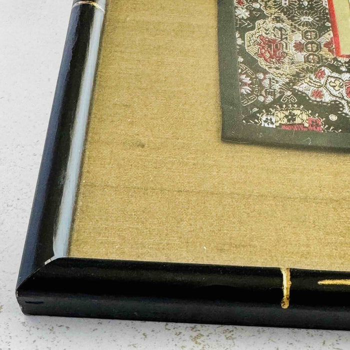 Close-up of corner of black and gold bamboo frame and gold silk texture mat