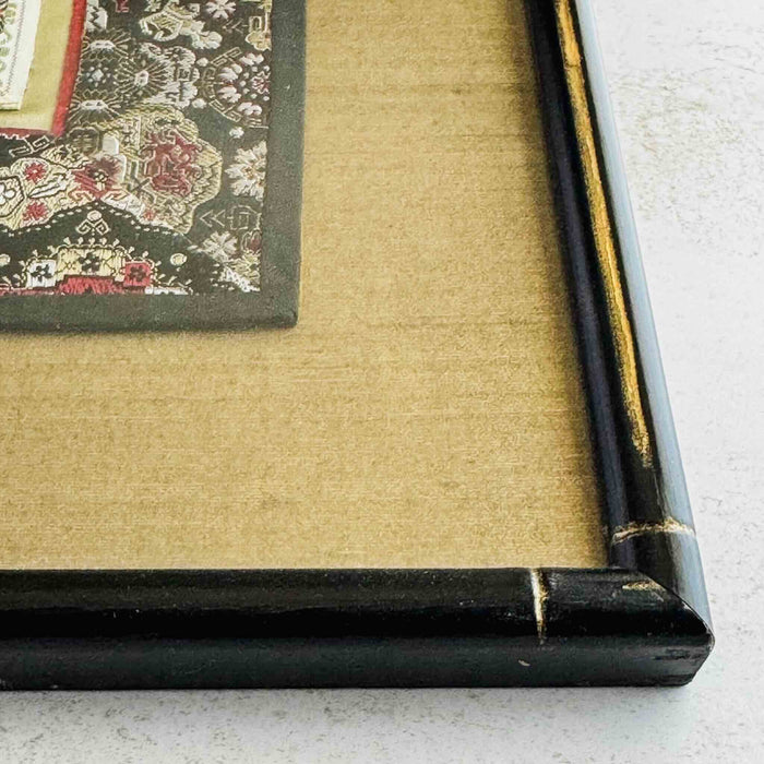 Close-up of corner of black and gold bamboo frame and gold silk texture mat