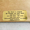 Close-up of gallery's gold label on back of framed embroidery