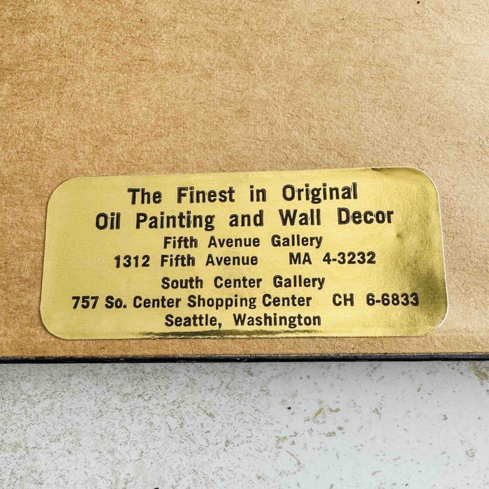 Close-up of gallery's gold label on back of framed embroidery