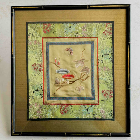 Framed embroidered fabric with floral and butterfly design on a light background