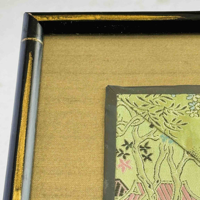 Close-up of corner of black and gold bamboo frame and gold silk texture mat