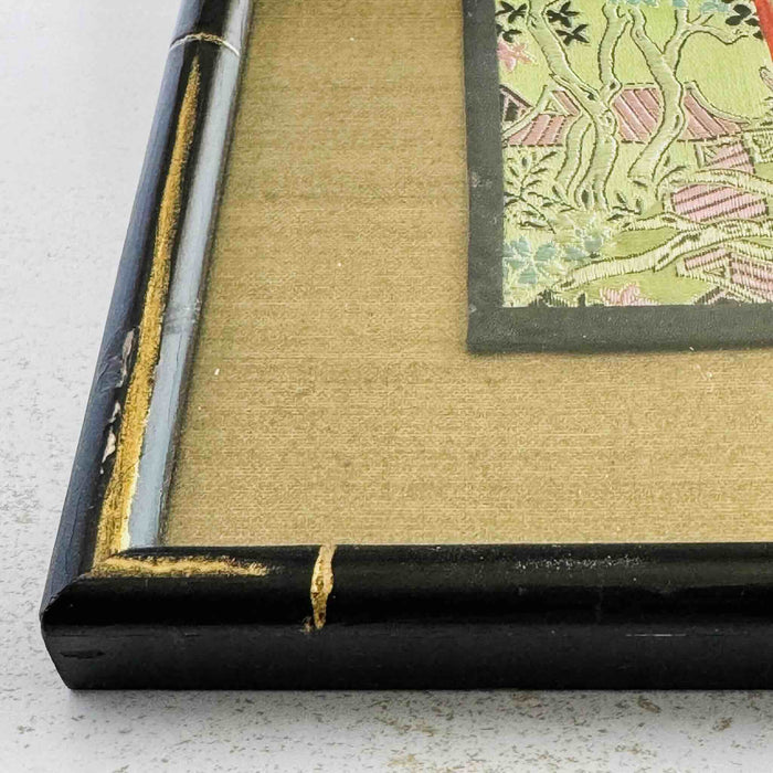 Close-up of corner of black and gold bamboo frame and gold silk texture mat showing scrape to frame