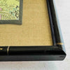 Close-up of corner of black and gold bamboo frame and gold silk texture mat