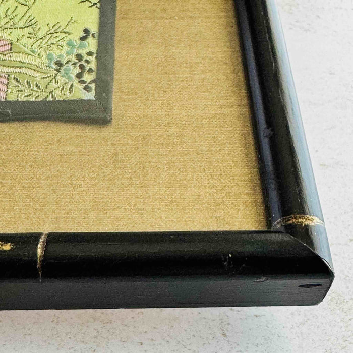 Close-up of corner of black and gold bamboo frame and gold silk texture mat