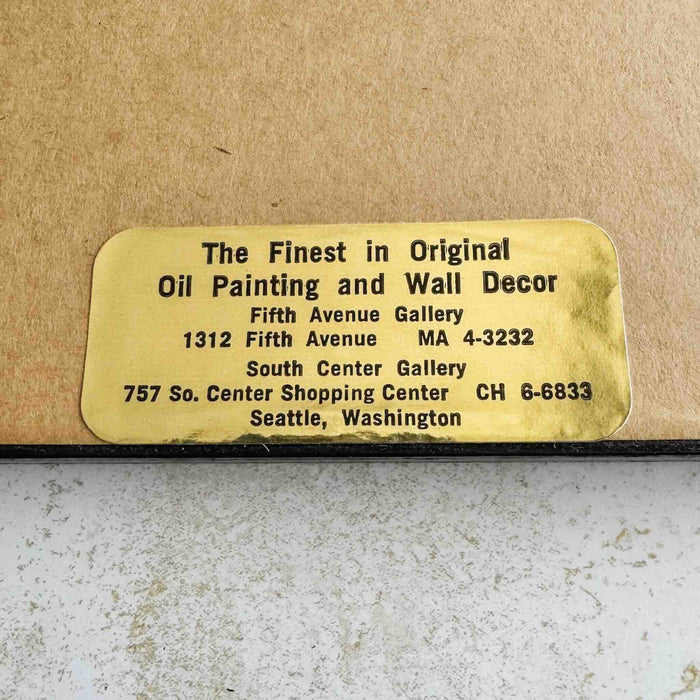 Close-up of gallery's gold label on back of framed embroidery