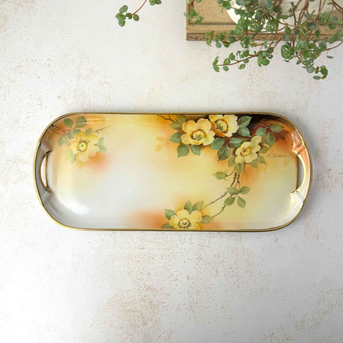 Overhead view of antique hand-painted porcelain tray with yellow roses, green leaves, gold trim, and integrated handles.