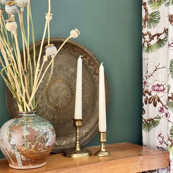 Vintage brass tray styled on a mantel beside a vase, candlesticks, and framed artwork