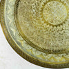 Close-up of the hand-tooled floral and geometric pattern in the lower-left section of the brass tray