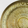 Close-up of the hand-tooled floral and geometric pattern in the upper-left section of the brass tray
