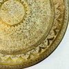 Close-up of the hand-tooled floral and geometric pattern in the lower-right section of the brass tray